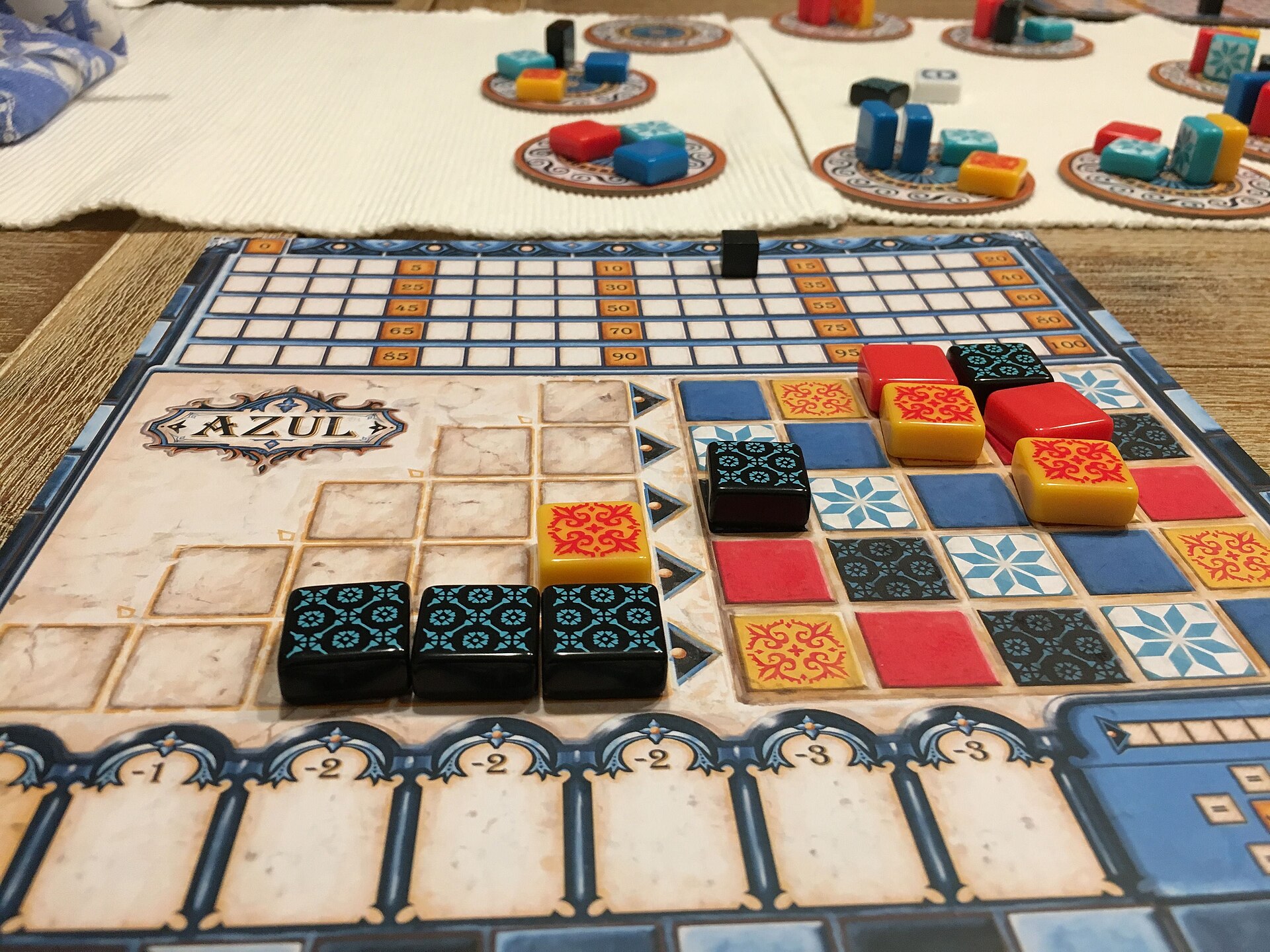 Four players around a tile-laying board game